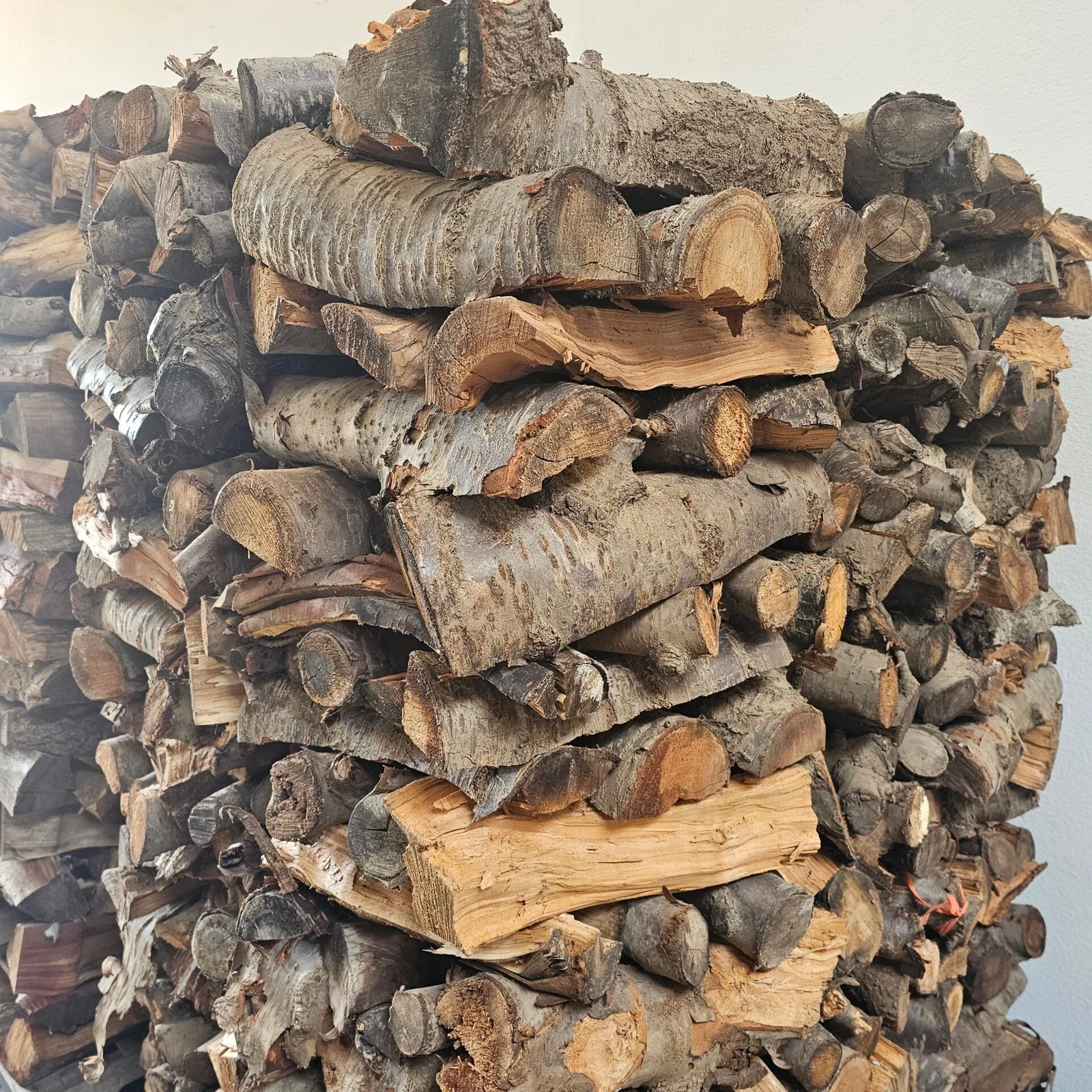 A neat stack of orange-wood logs waiting by the kitchen wall