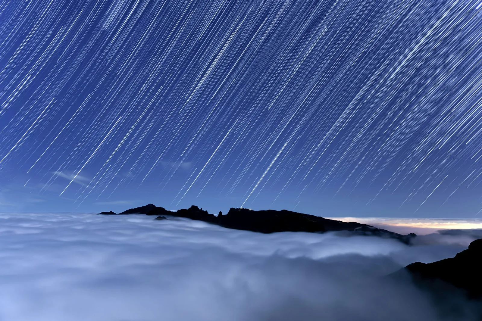 Star trails circling above a sea of clouds over the ridge