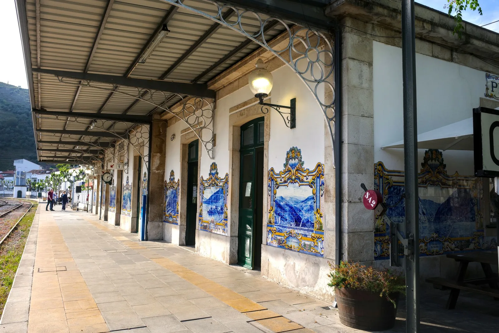 The platform at Pinhão station, with blue-and-white azulejo tiles showing the river and the harvest, and a single bench under a wrought-iron canopy.